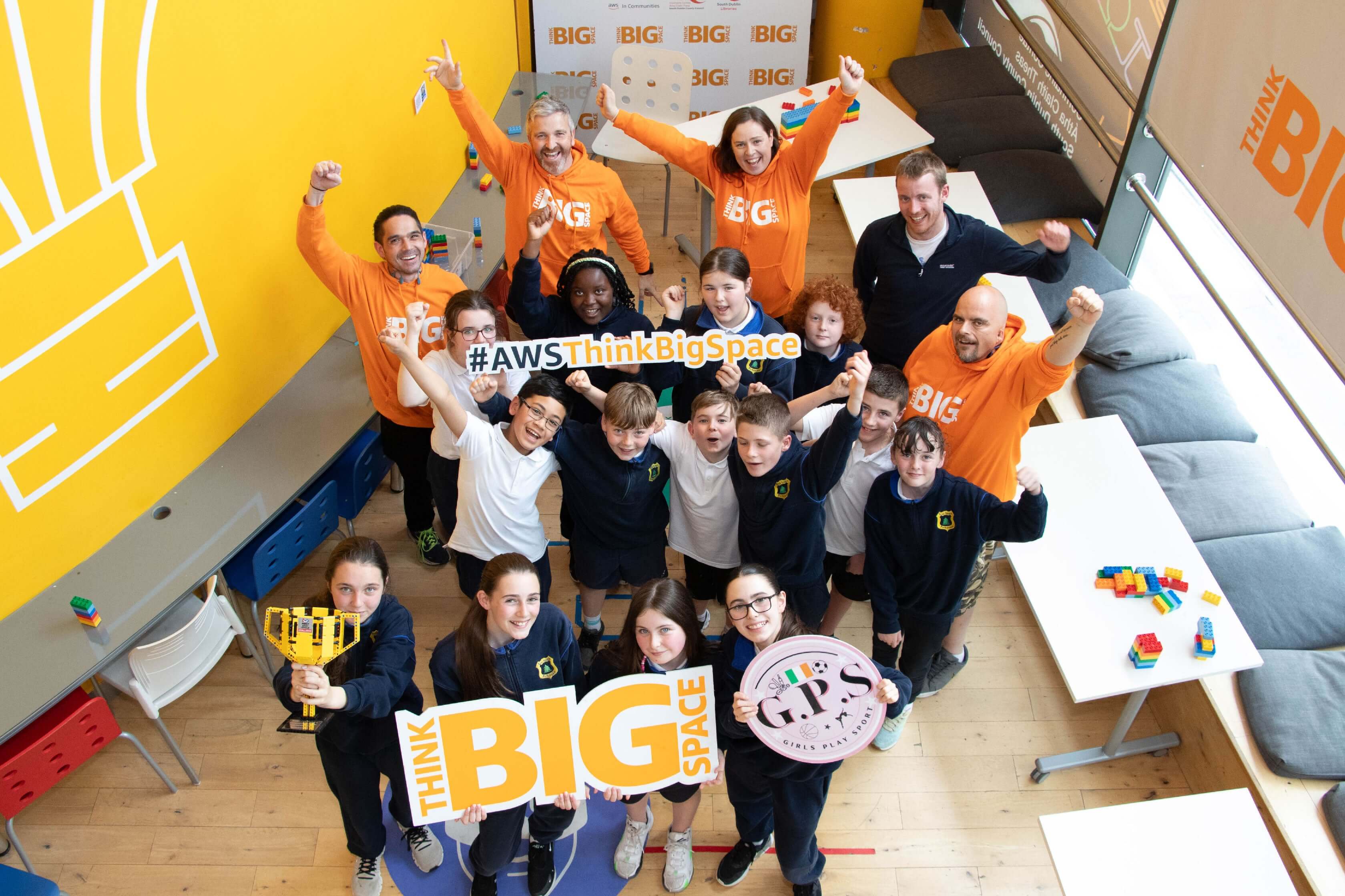 Group of students and mentors celebrating STEAM education at AWS Think Big Space event.