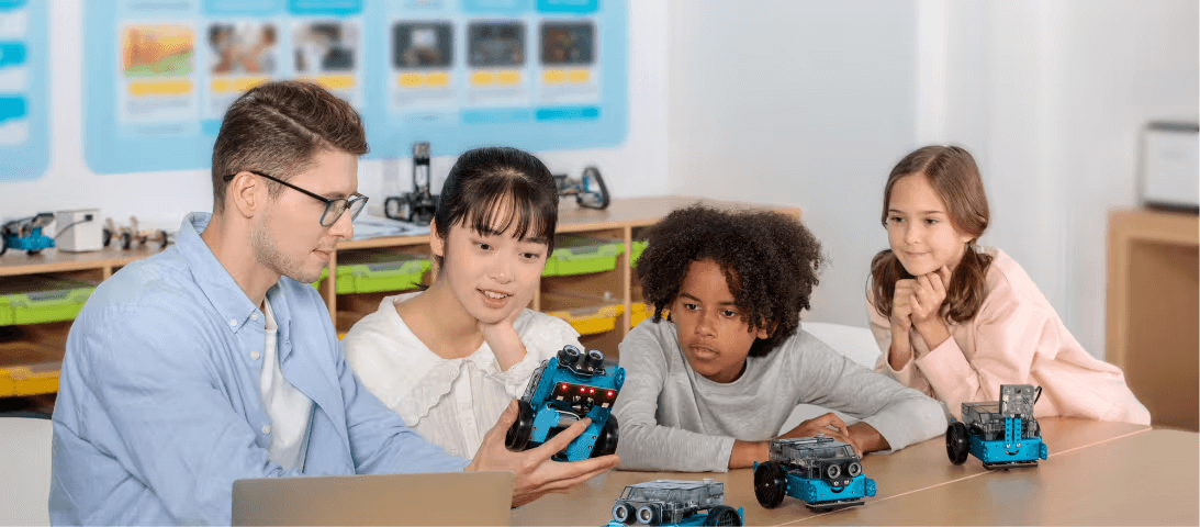Educator engaging students with Makeblock robotics kits in a classroom setting.