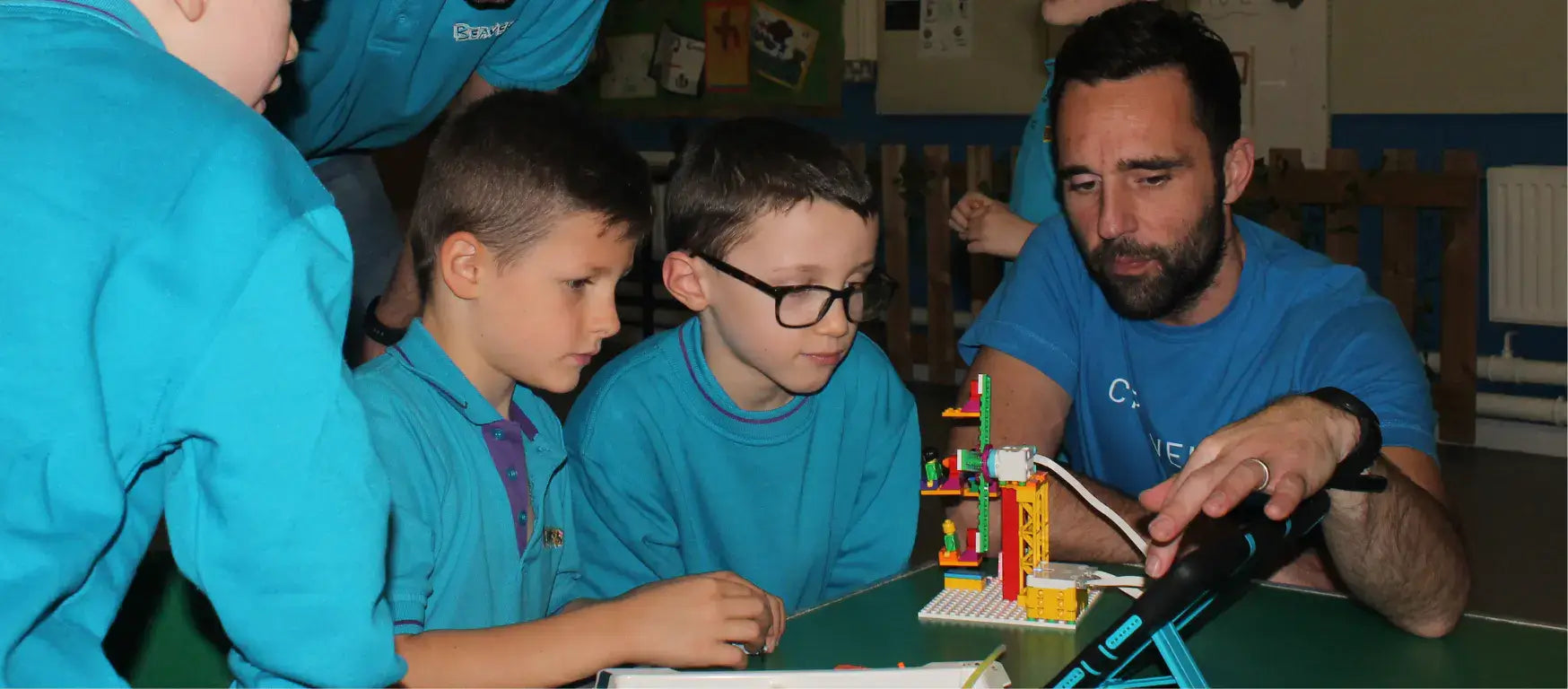 Beaver Scouts engaged in a LEGO Education SPIKE Essential coding workshop with an instructor guiding them.