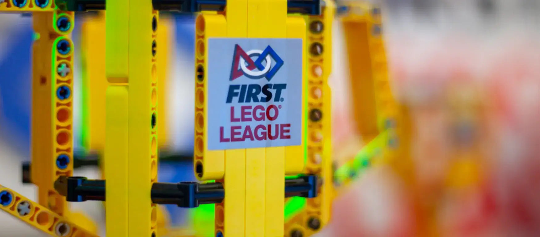 Close-up of FIRST LEGO League logo on colorful LEGO structure during a STEAM education event.