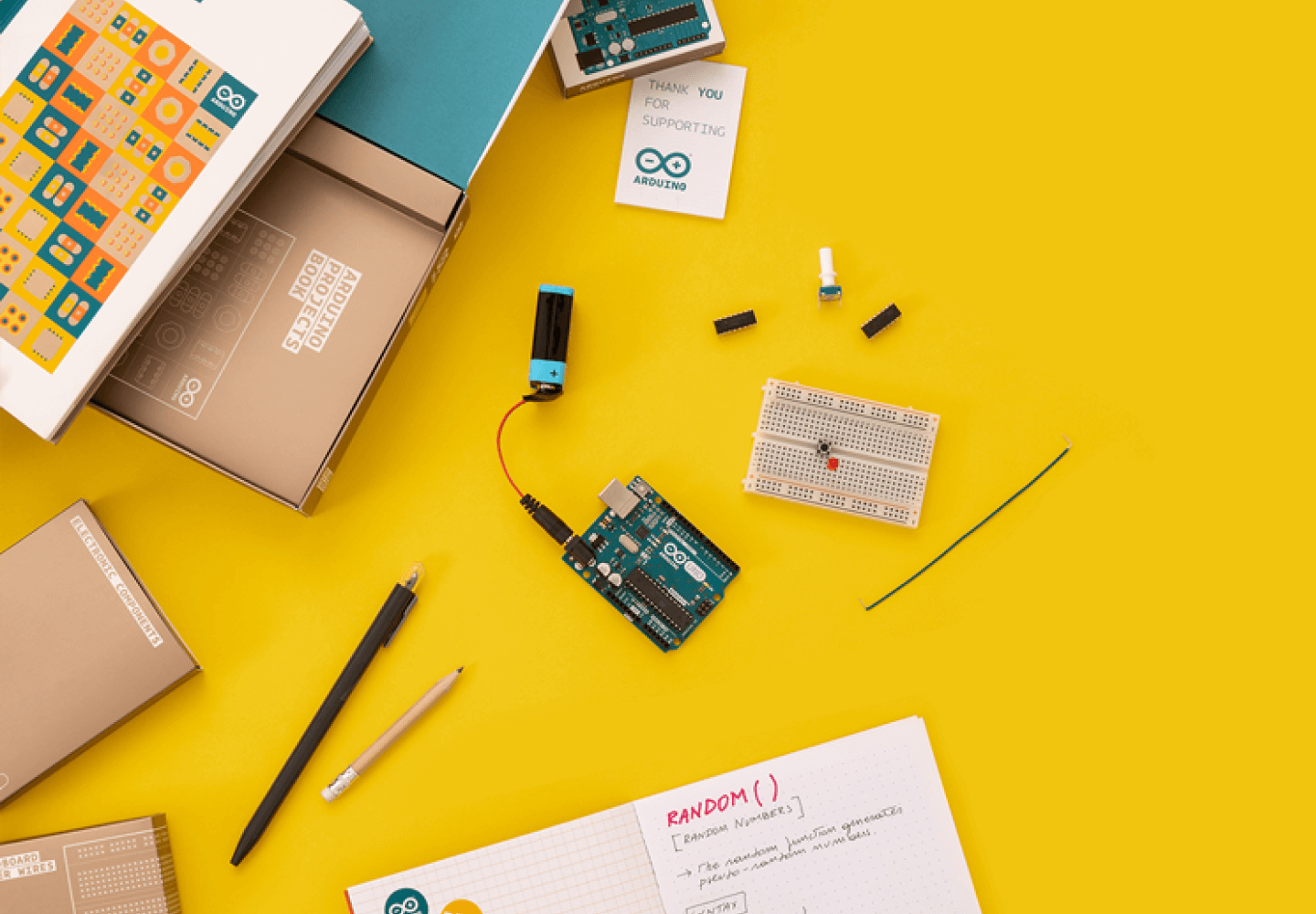 Flat lay of Arduino components and tools on a bright yellow background, showcasing electronics and creativity.