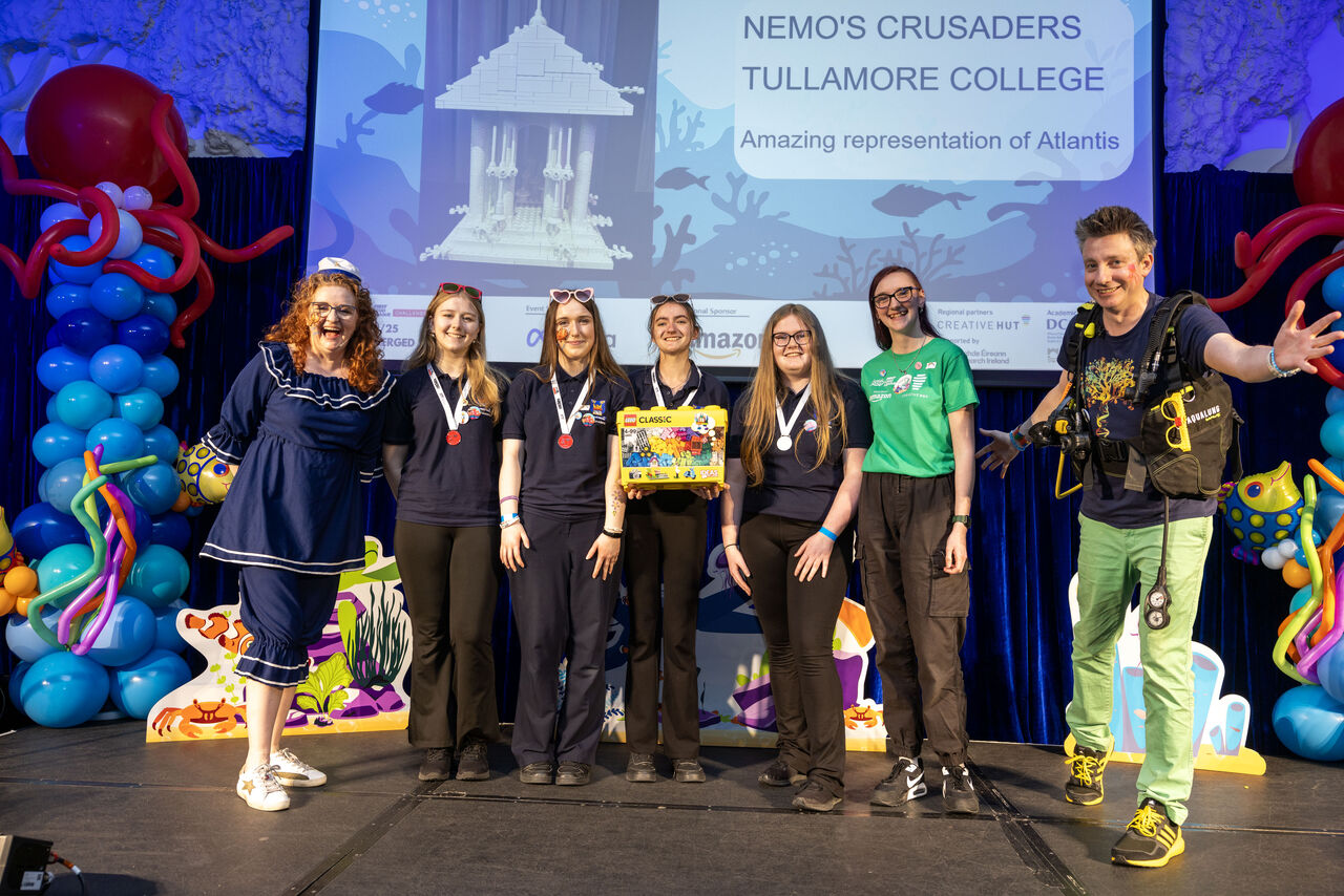 Team from Tullamore College celebrating with medals at a colorful event showcase for Atlantis-themed project.