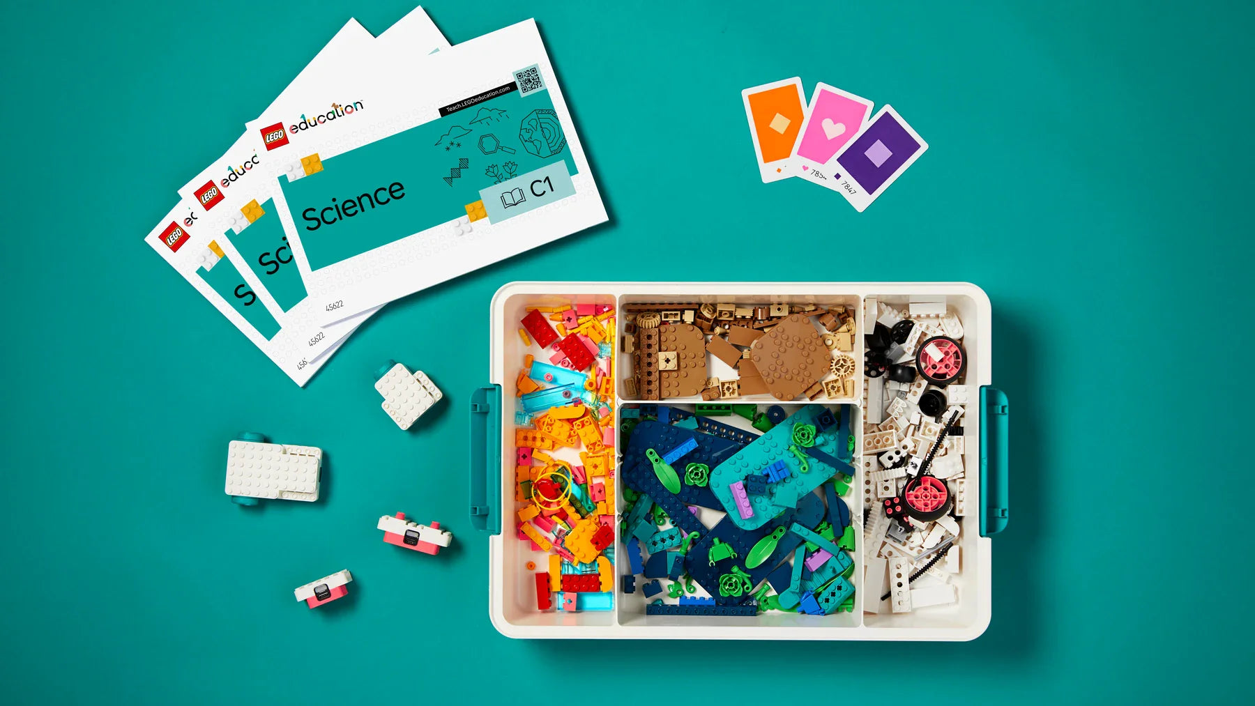 Colorful educational LEGO set for science learning with cards and building pieces on a teal background.
