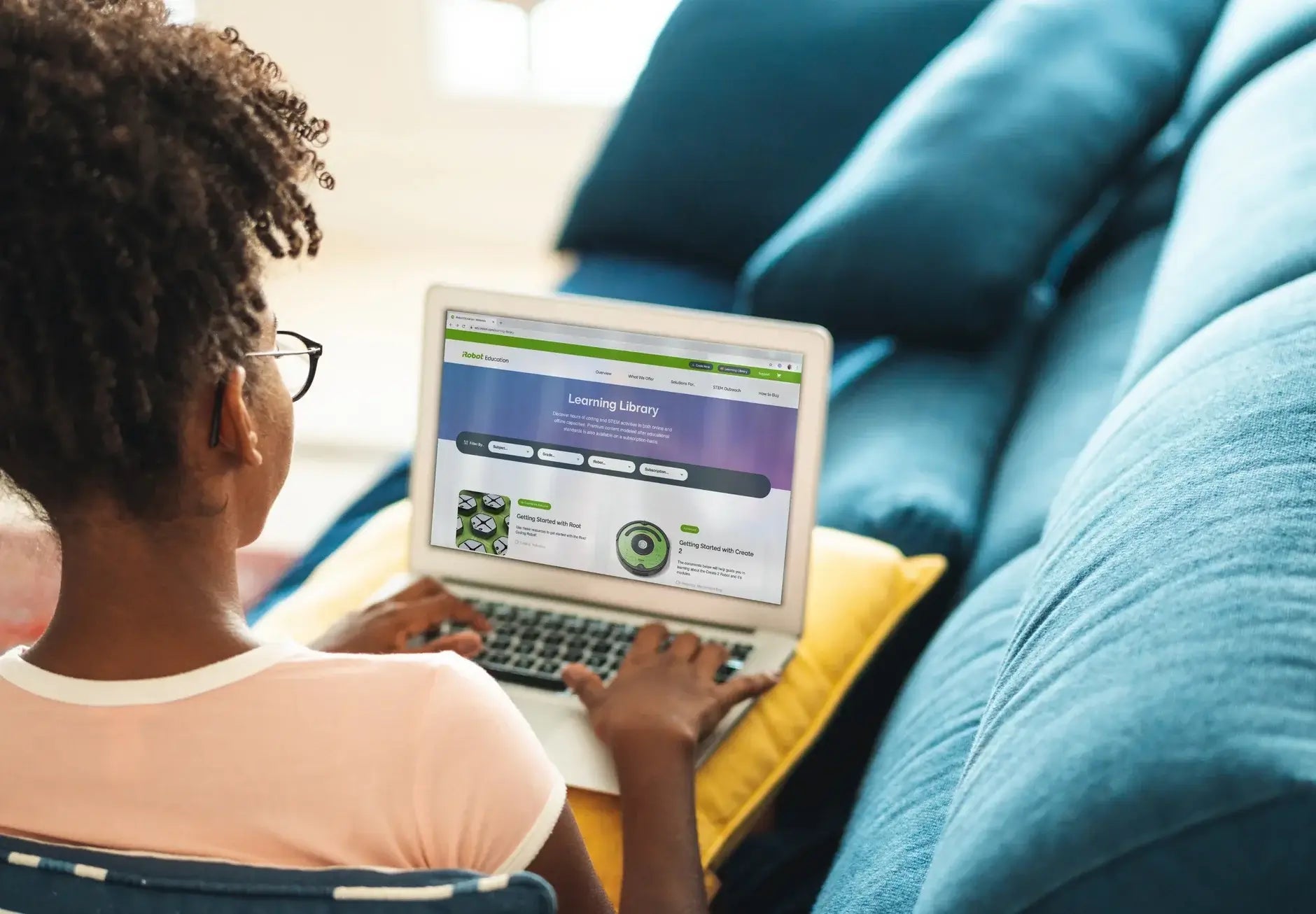Girl using a laptop on a couch, engaging with an online learning library platform.