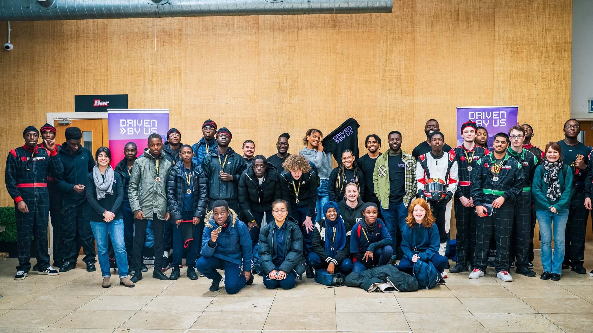 Group photo of diverse individuals at an event, standing together with purple banners in the background.