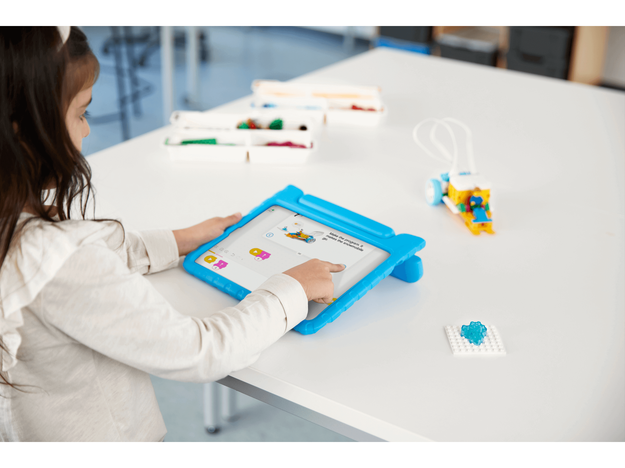 Child interacting with tablet while using LEGO® Education SPIKE™ Essential Set for STEAM learning.