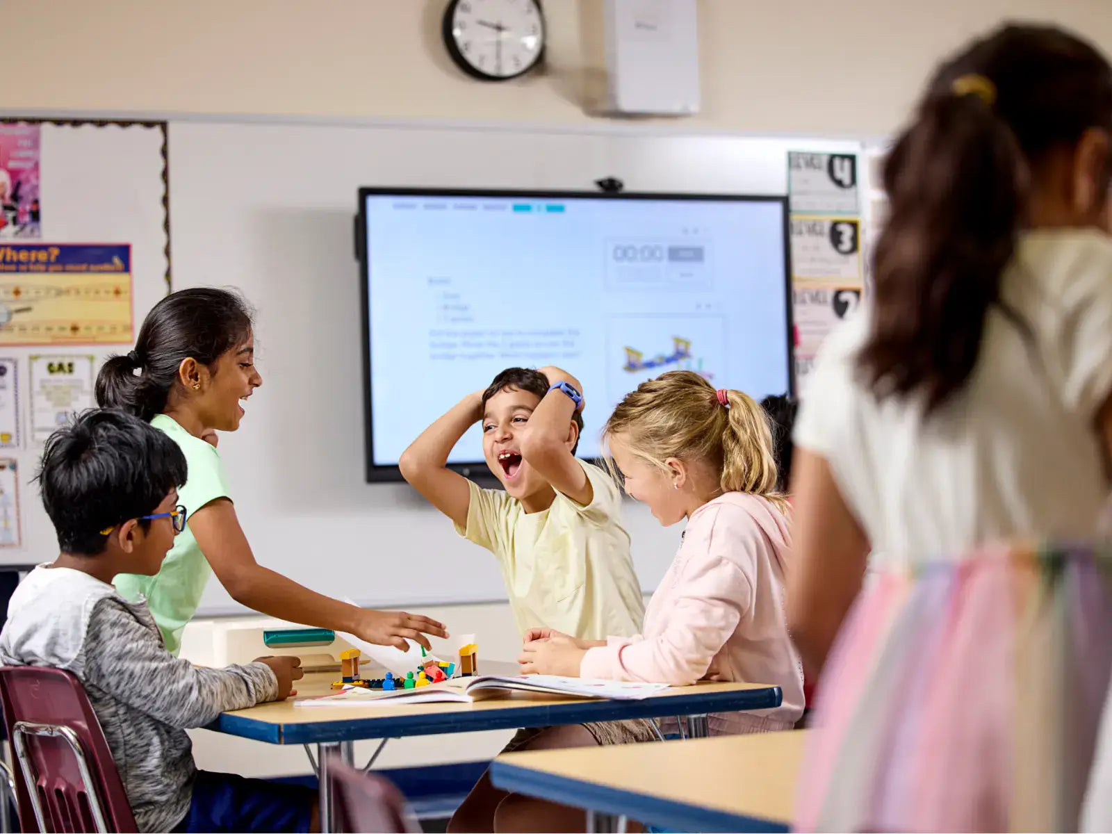 Children engaging in fun learning activities in a classroom with digital screen and diverse educational tools.