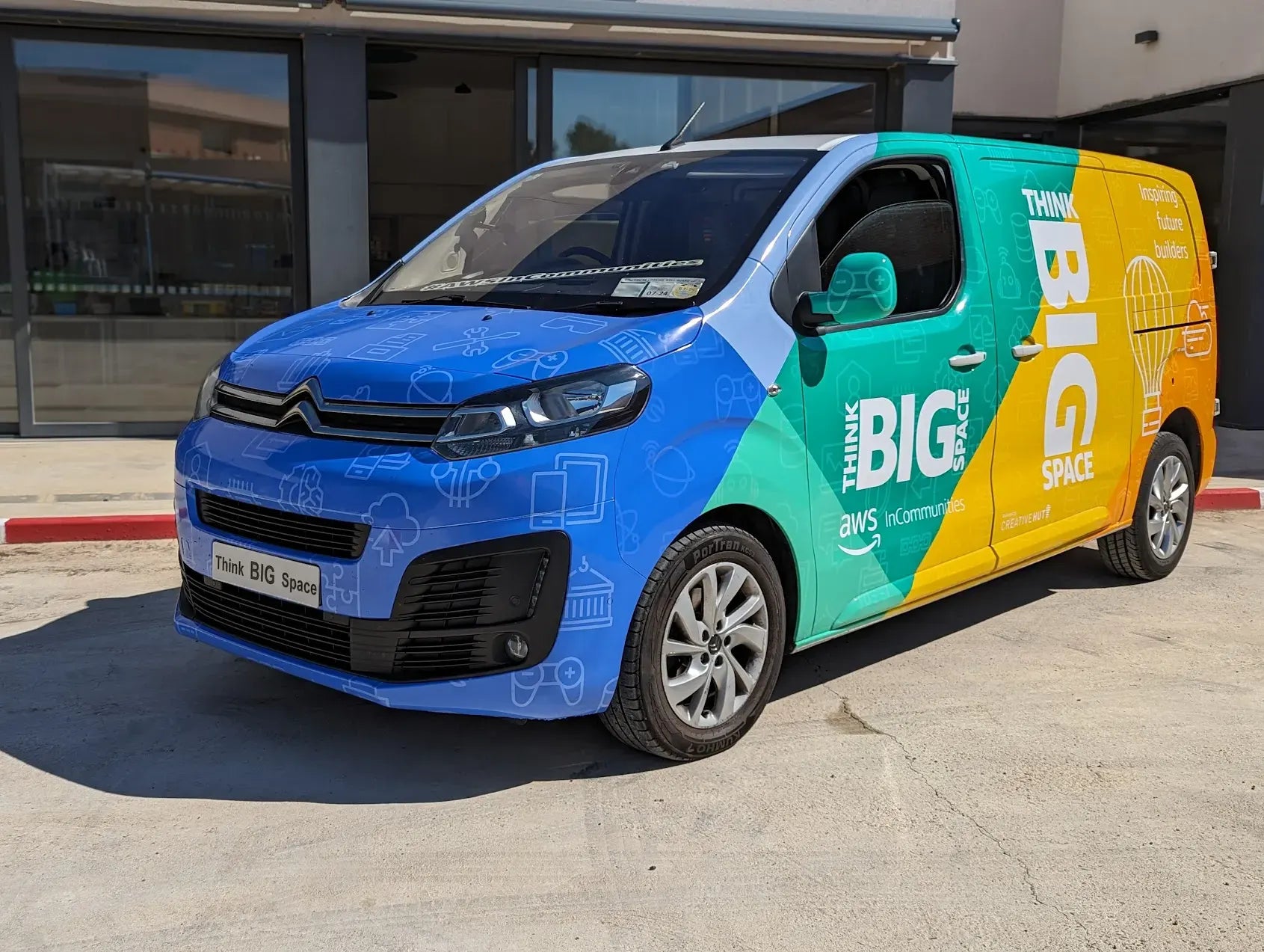 Colorful Citroën van with 'Think BIG Space' branding, parked outside a building.