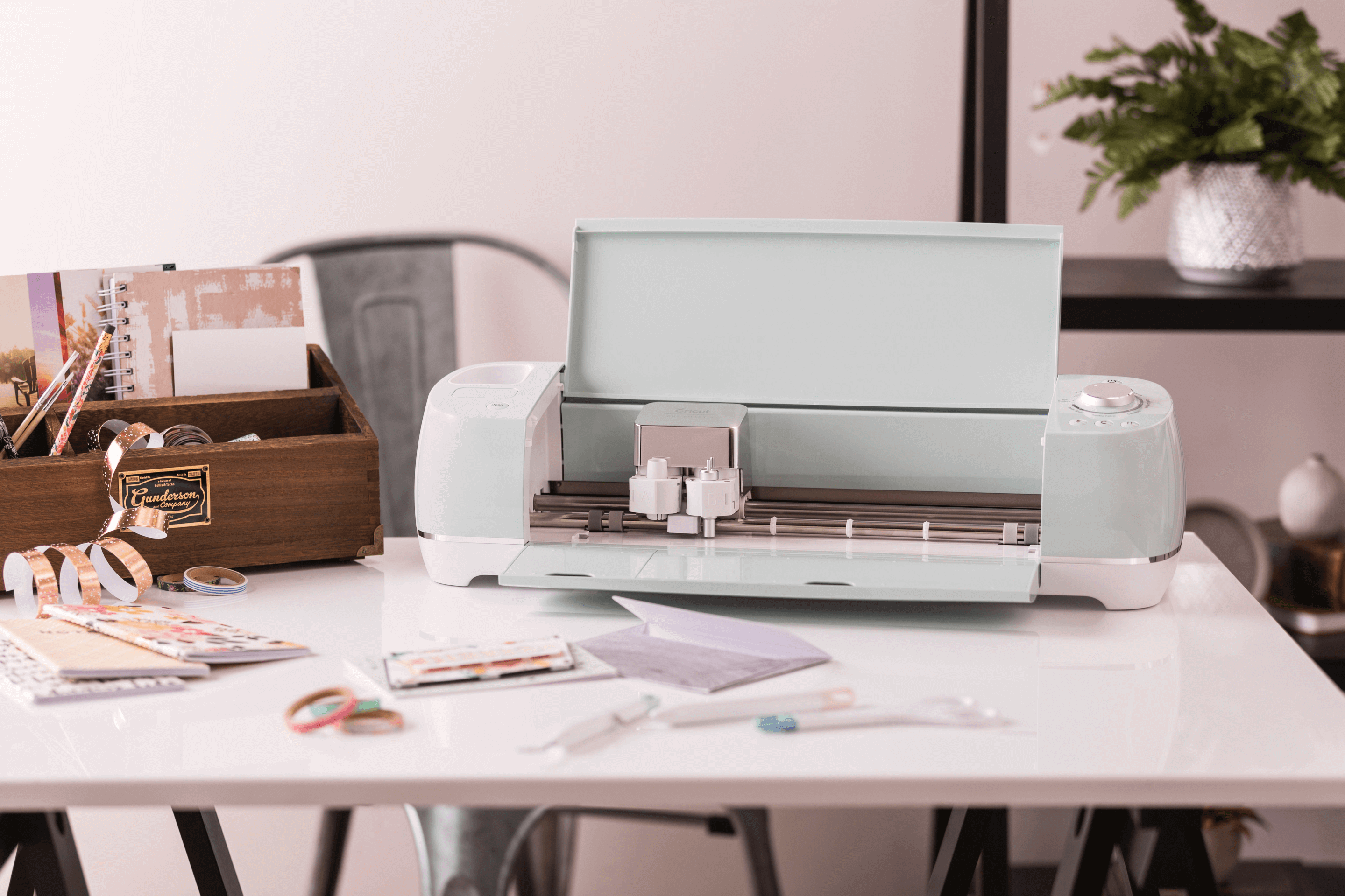 Cricut Explore Air 2 in mint color displayed on a desk with crafting supplies and materials around it.