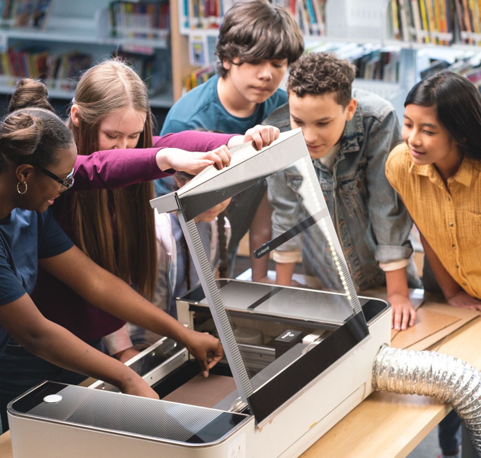 Students engaged in a hands-on learning activity with a machine in a library setting.