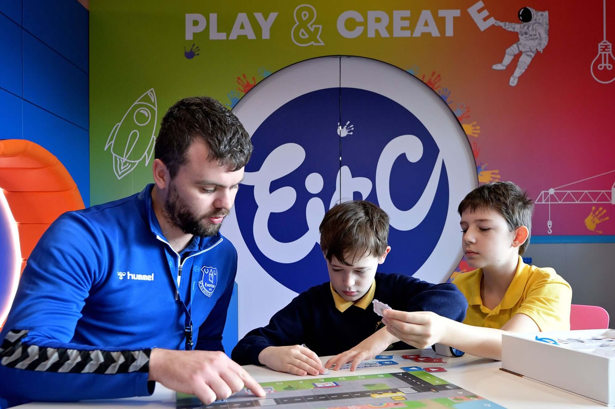 Teacher and two students engaged in creative learning at a colorful educational center.