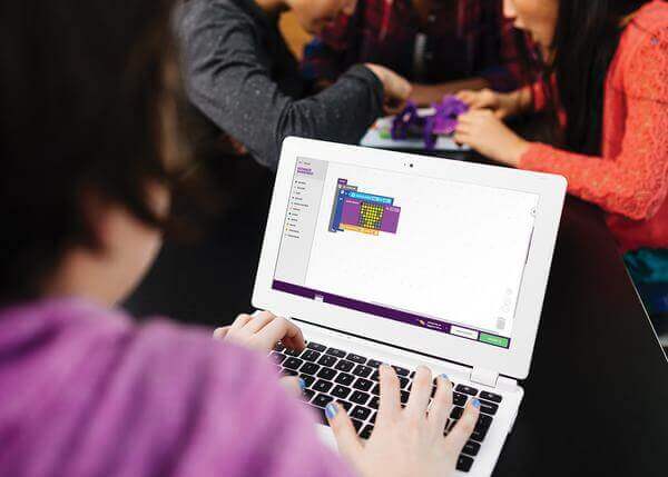 Student coding with littleBits Code Kit on a laptop while classmates engage in hands-on STEM activities.