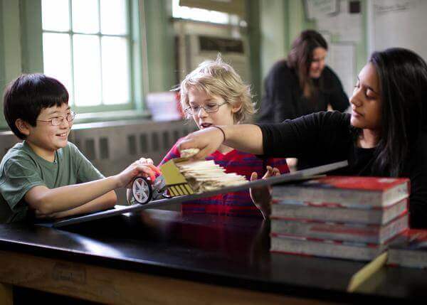 Two children engaging in hands-on engineering activities with an educator using the littleBits STEAM Student Set.
