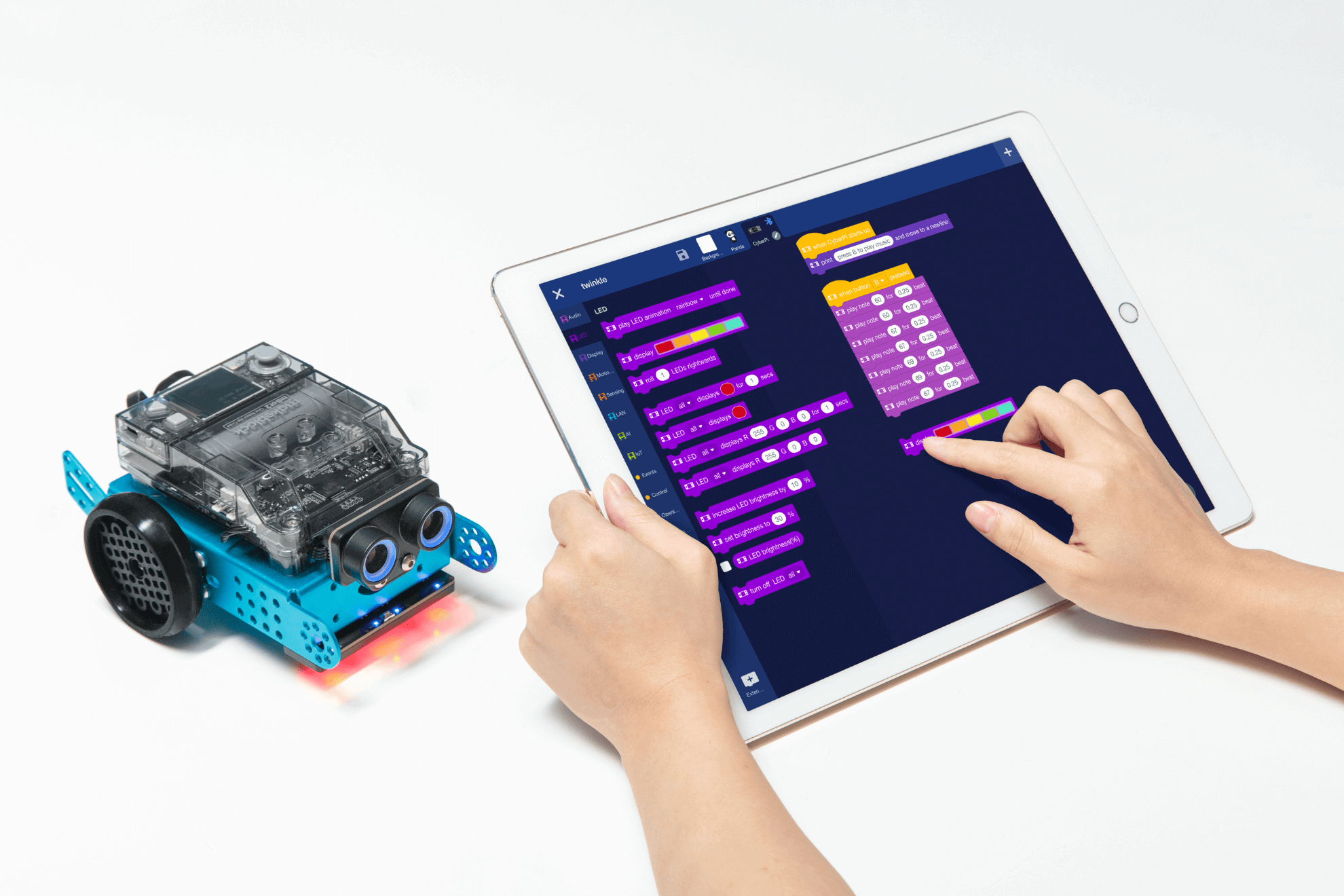 Student programming the Makeblock mBot 2 educational robot using a tablet screen with coding interface.