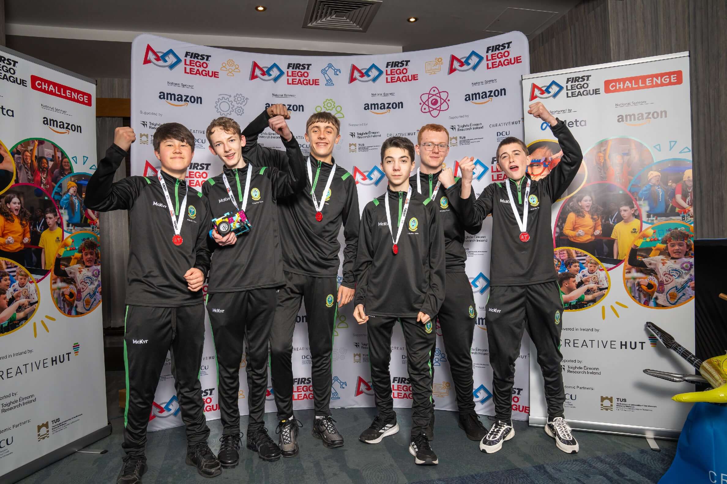Group of young competitors celebrating with medals at the FIRST LEGO League event, showcasing teamwork and innovation.