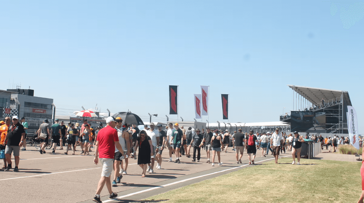 Large crowd at a sports event walking along a pathway under a clear blue sky.