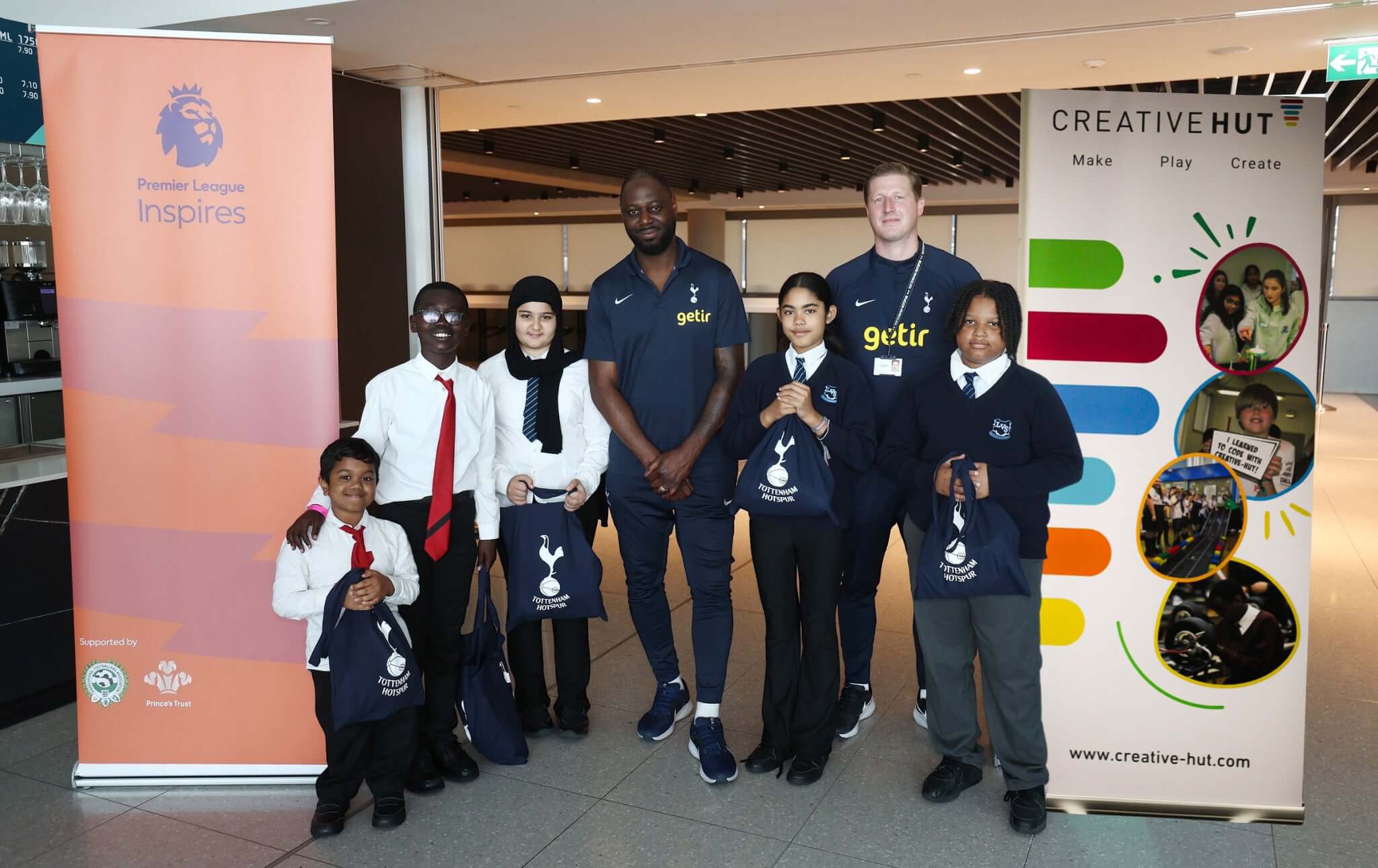 Group of children with adults at a community event, promoting creativity and education with banners.