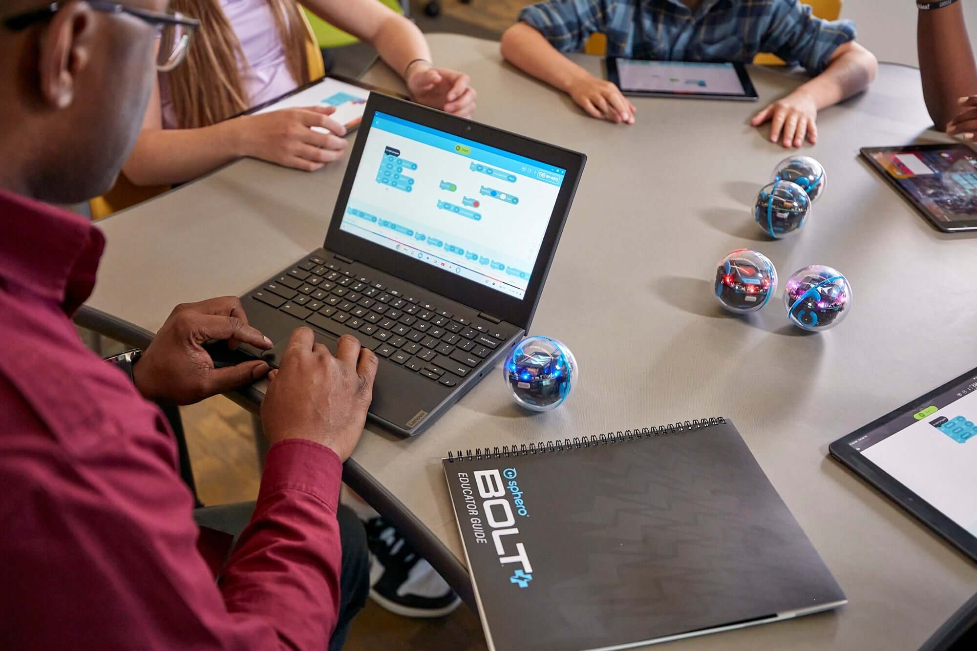 Student programming Sphero BOLT+ robots on a laptop, enhancing coding skills with hands-on learning.