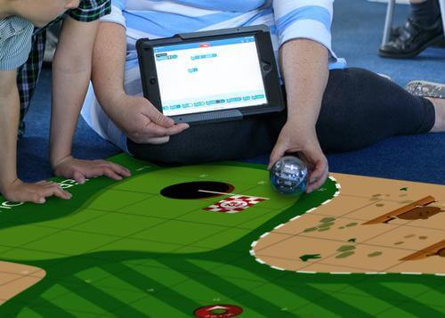 Child and adult using Sphero Code Mat with coding tablet and robot, engaging in interactive learning.