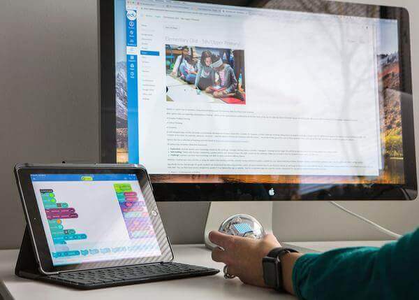 Person using a tablet for Block Based programming alongside a computer displaying Sphero Fundamentals course.