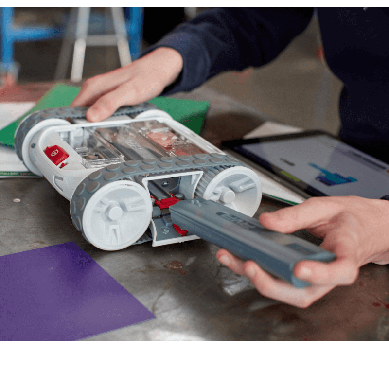 Hands inserting battery into Sphero RVR+ programmable robot, showcasing its customizable design and technology.