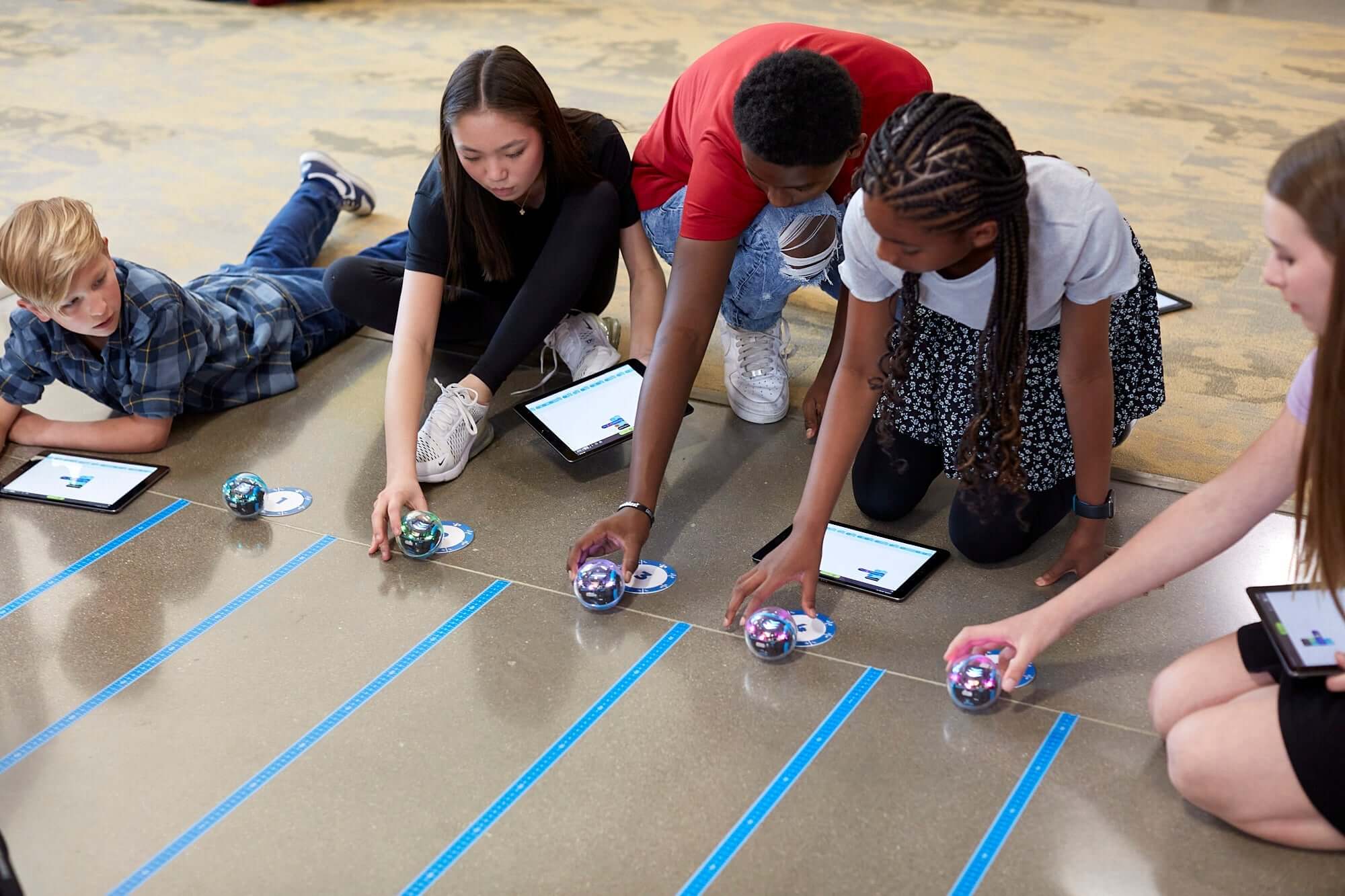 Students programming Sphero BOLT+ robots on a classroom floor with tablets for hands-on STEM learning.