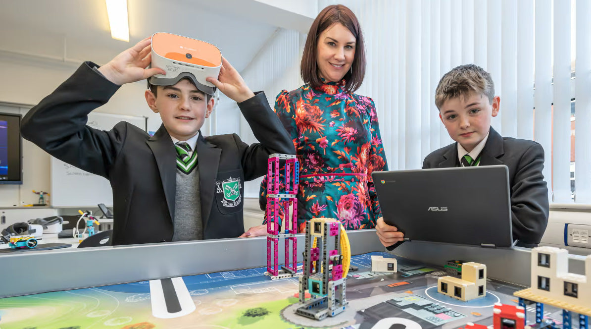 Students using VR technology and a laptop in an innovative classroom with a teacher engaging them in learning.