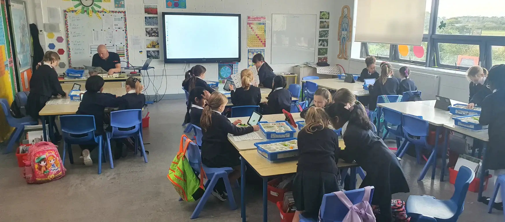 Students in a classroom engaged in creative learning activities during CreativeHUT workshops.
