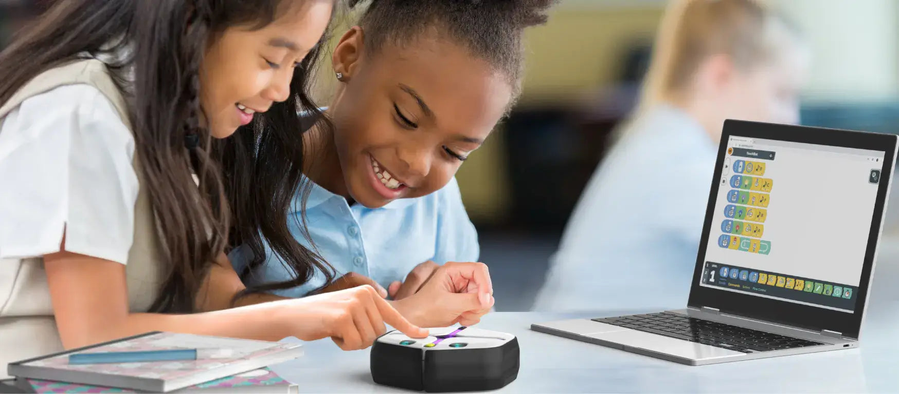 Two children engaging with a Root coding robot while using a laptop for programming.