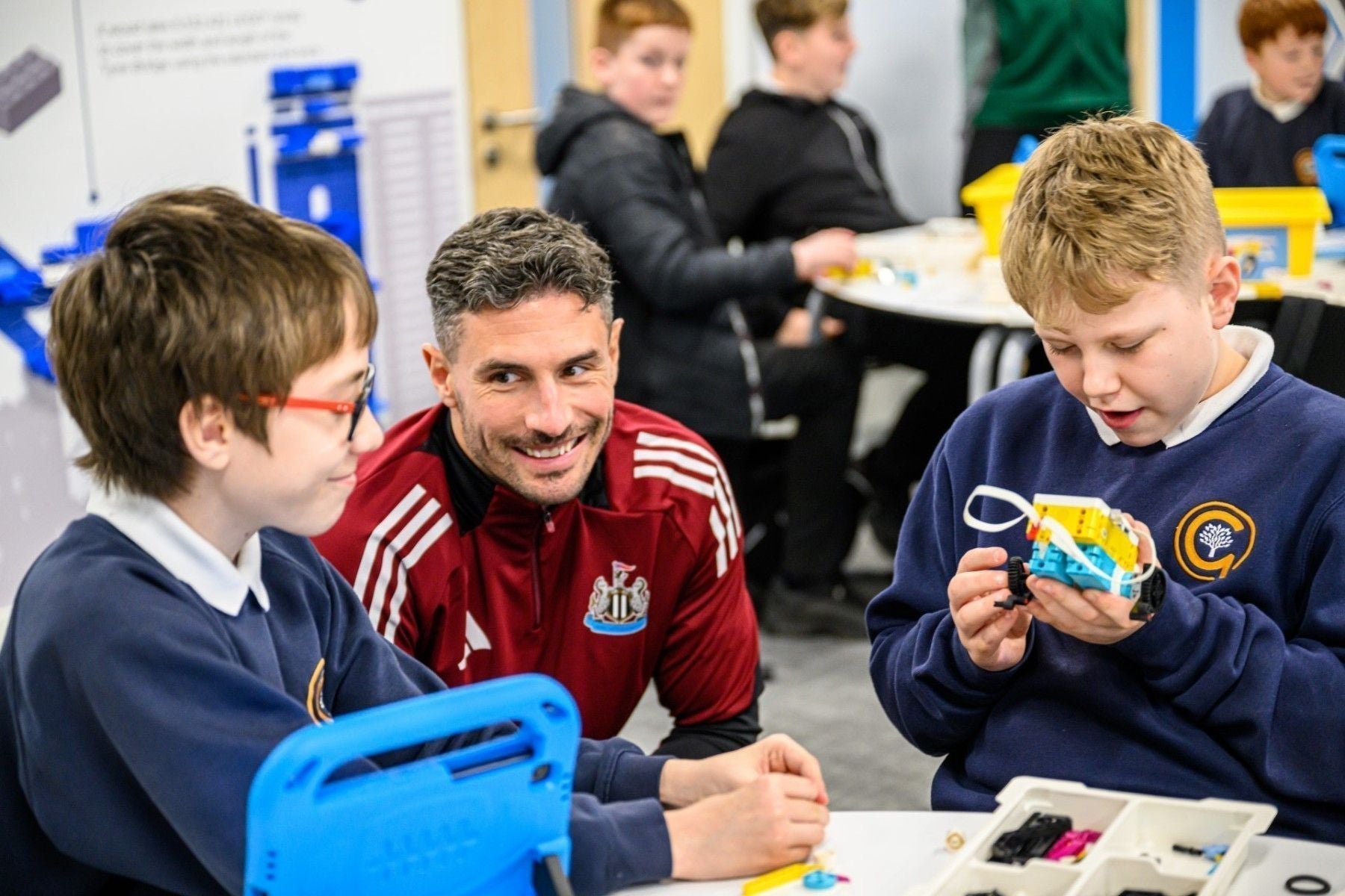 Students engaging in STEM activities at Newcastle United Foundation, guided by a mentor.