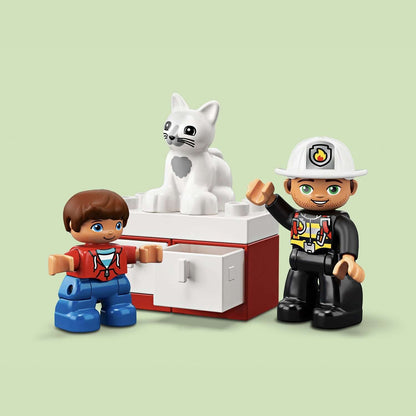LEGO® DUPLO Town Fire Truck set 10901 with firefighter and boy beside cat on tree trunk in vibrant colors.