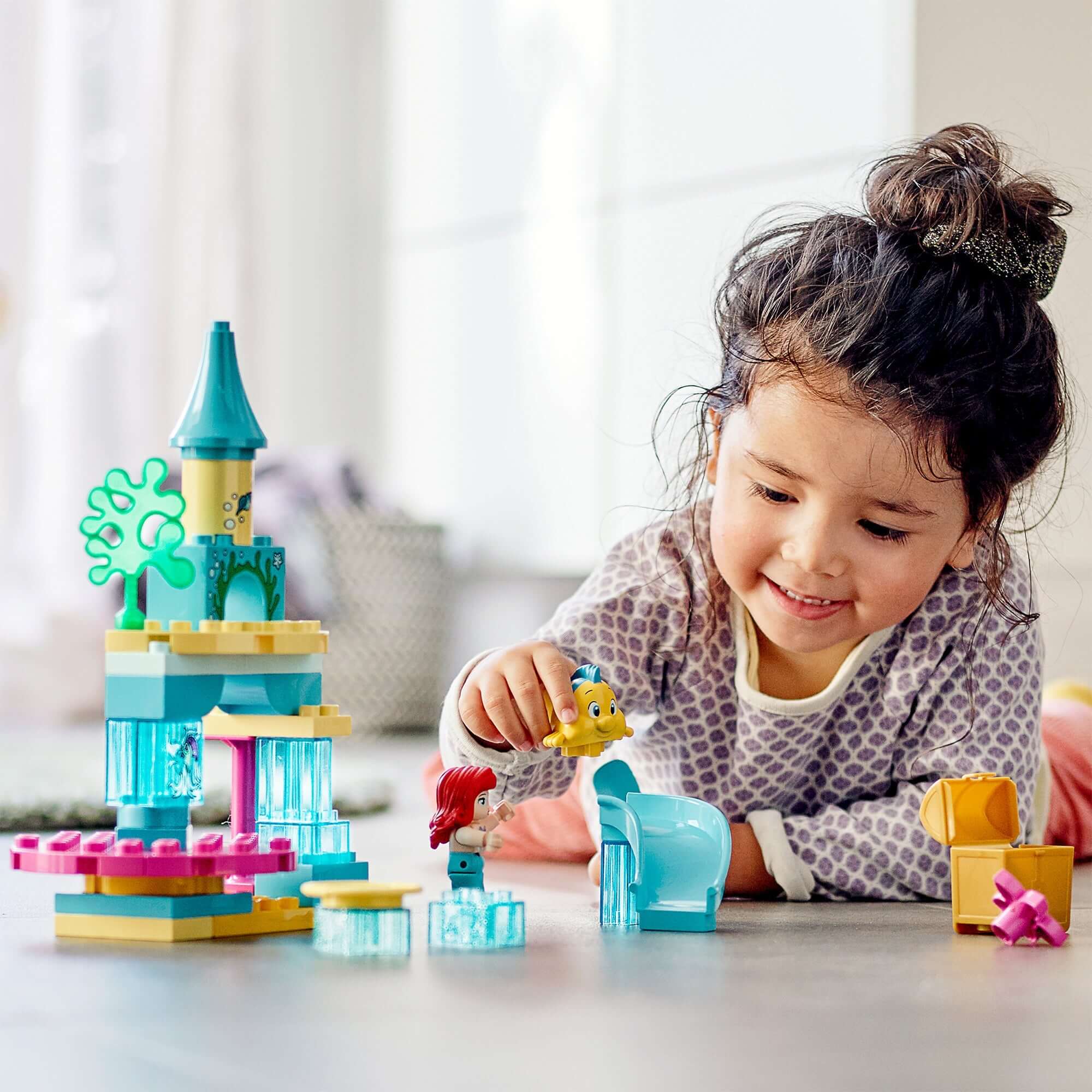 Child playing with LEGO® DUPLO Princess Ariel Undersea Castle Set, featuring Ariel and Flounder, promoting imaginative roleplay.