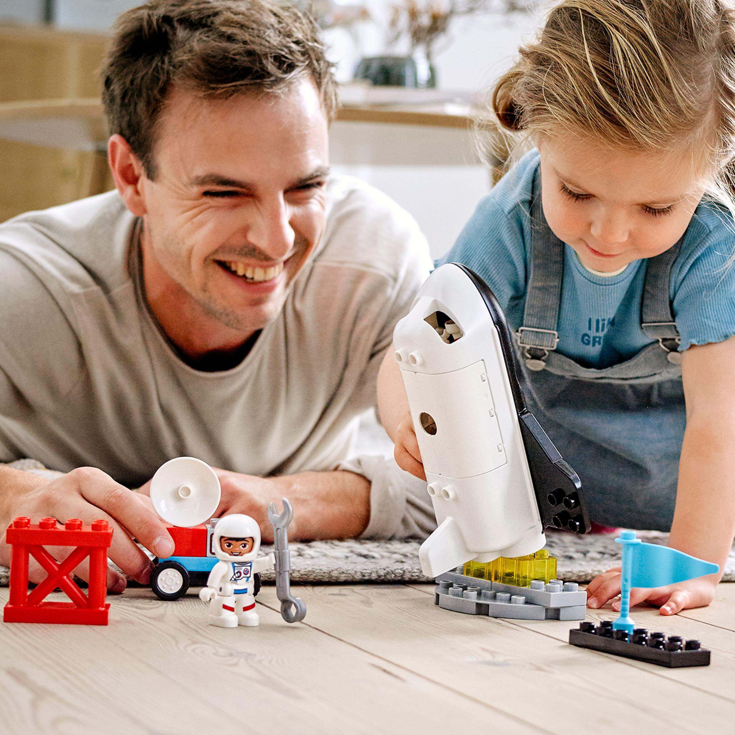 A father and daughter enjoying the LEGO® DUPLO Space Shuttle Mission set, fostering creativity and developmental skills together.