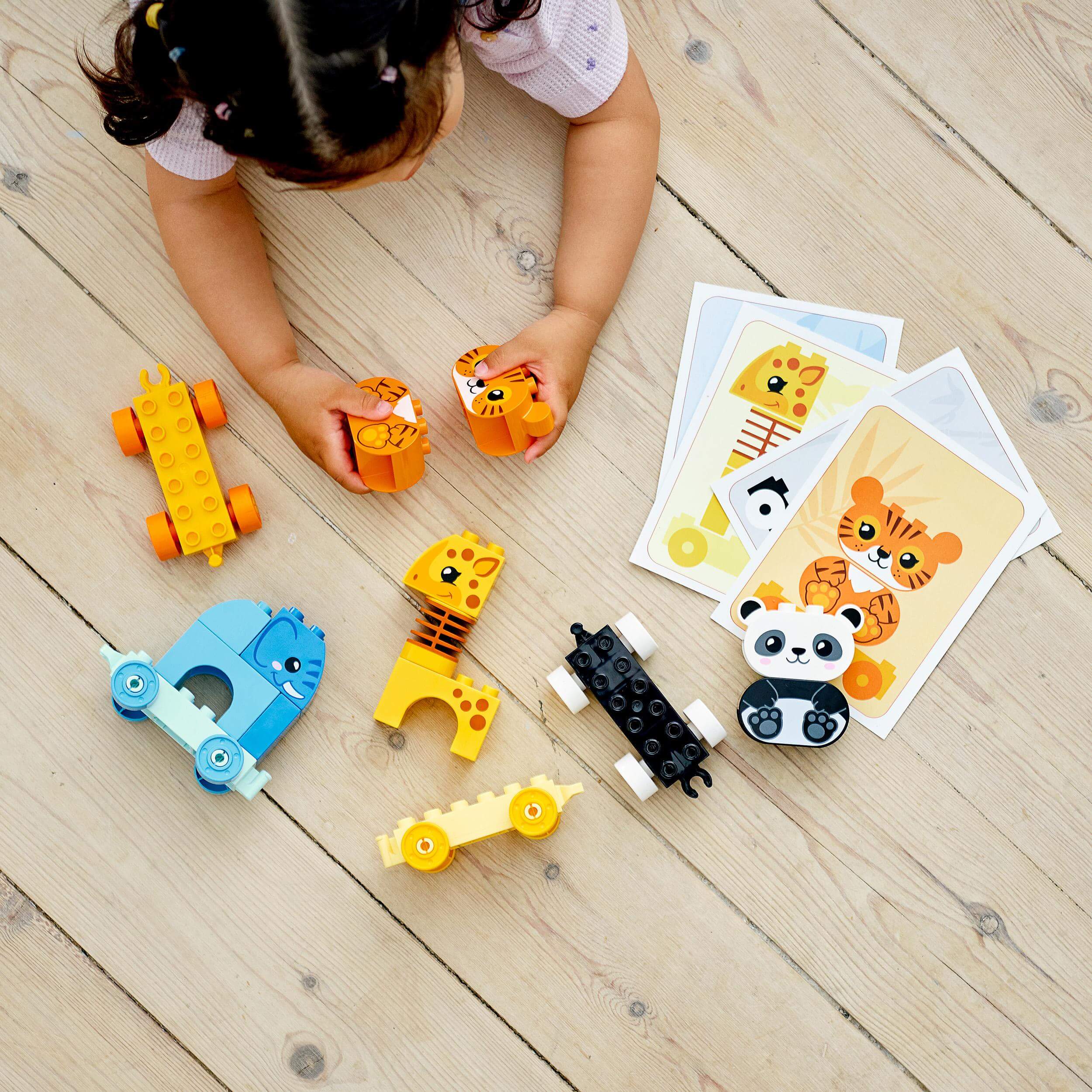Child playing with LEGO® DUPLO My First Animal Train Toy 10955, featuring colorful animal pieces and cards.