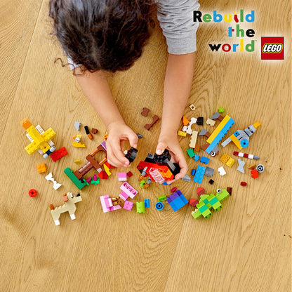 Child playing with colorful LEGO bricks on a wooden floor, exploring creativity with the LEGO Classic Basic Brick Set 11002.
