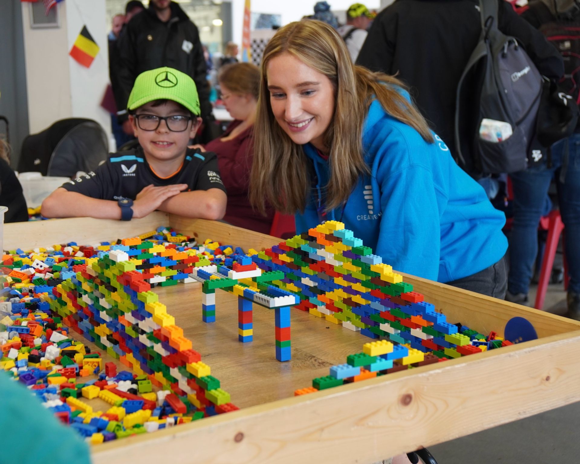 Two children engaging with a colorful LEGO creation at an event, showcasing creativity and fun.