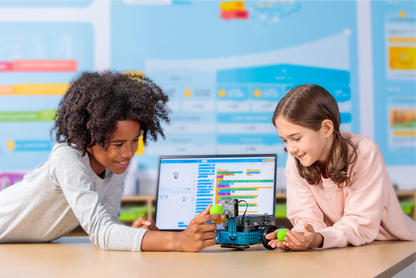 Two children engaging with the Makeblock mBot 2 robot and a laptop, fostering STEM education and creativity.