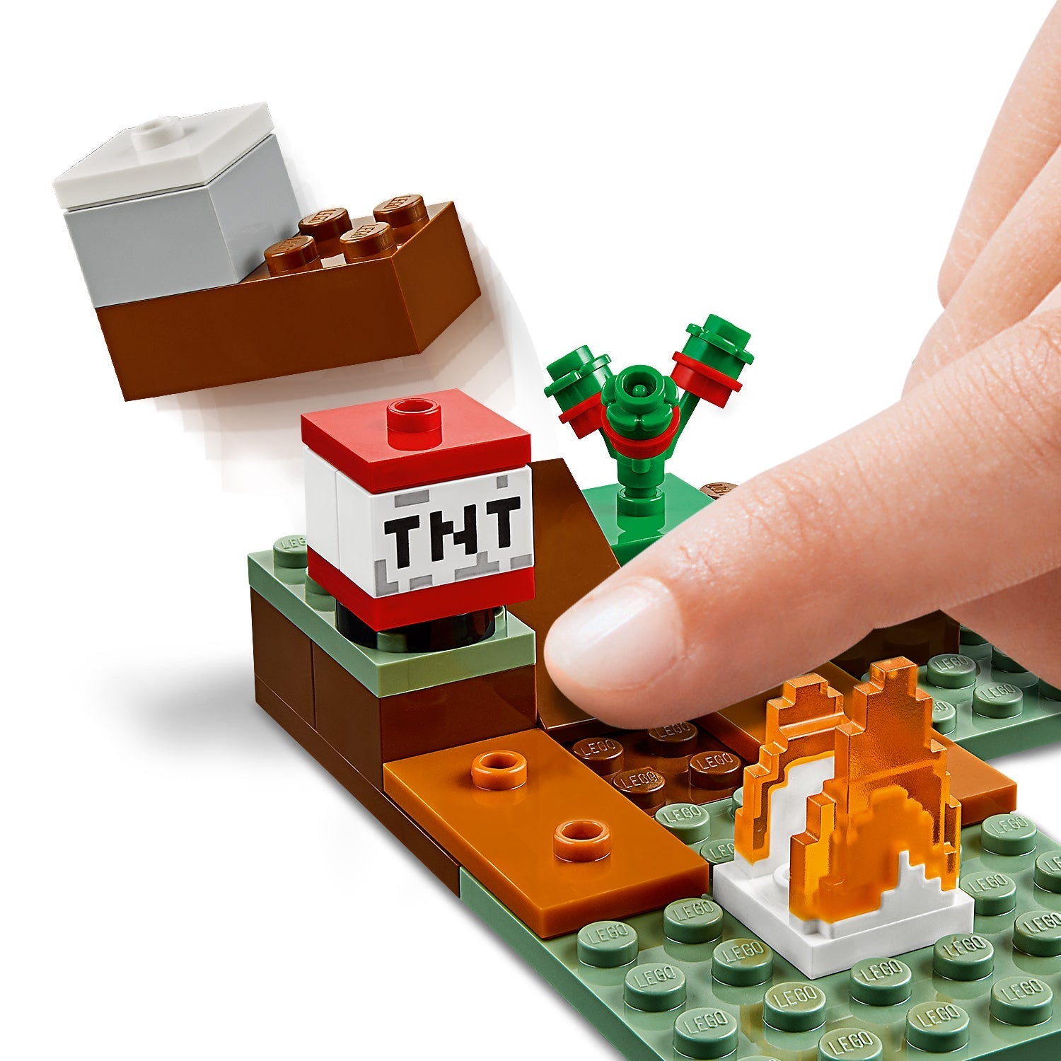 Finger pressing on LEGO® Minecraft set with TNT block and fire in the Taiga Adventure set.