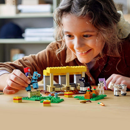 Child playing with LEGO® Minecraft The Horse Stable Farm Toy 21171, constructing obstacle courses and enjoying the game.