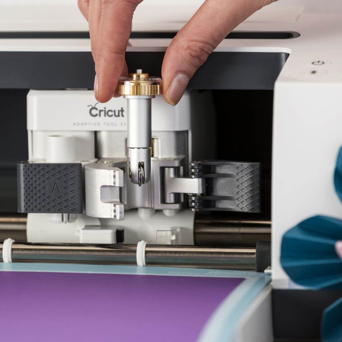 A hand attaching a scoring wheel to a Cricut Maker for crafting projects.
