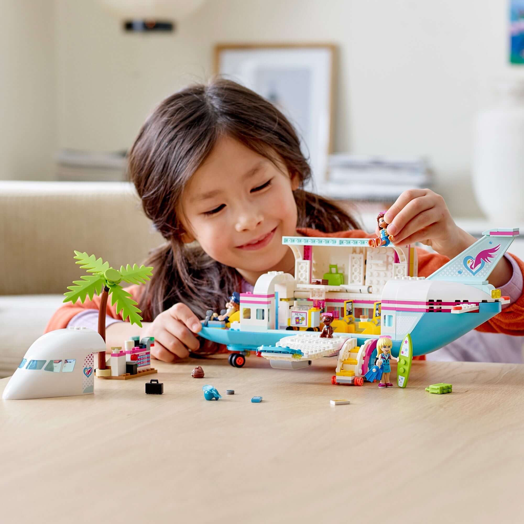 Child playing with LEGO® Friends Heartlake City Aeroplane Play Set 41429, featuring an airplane and accessories.