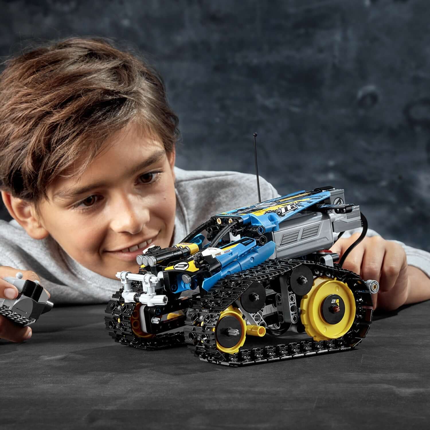 Boy playing with LEGO Technic Stunt Racer RC car 42095, showcasing hands-on fun and creativity.