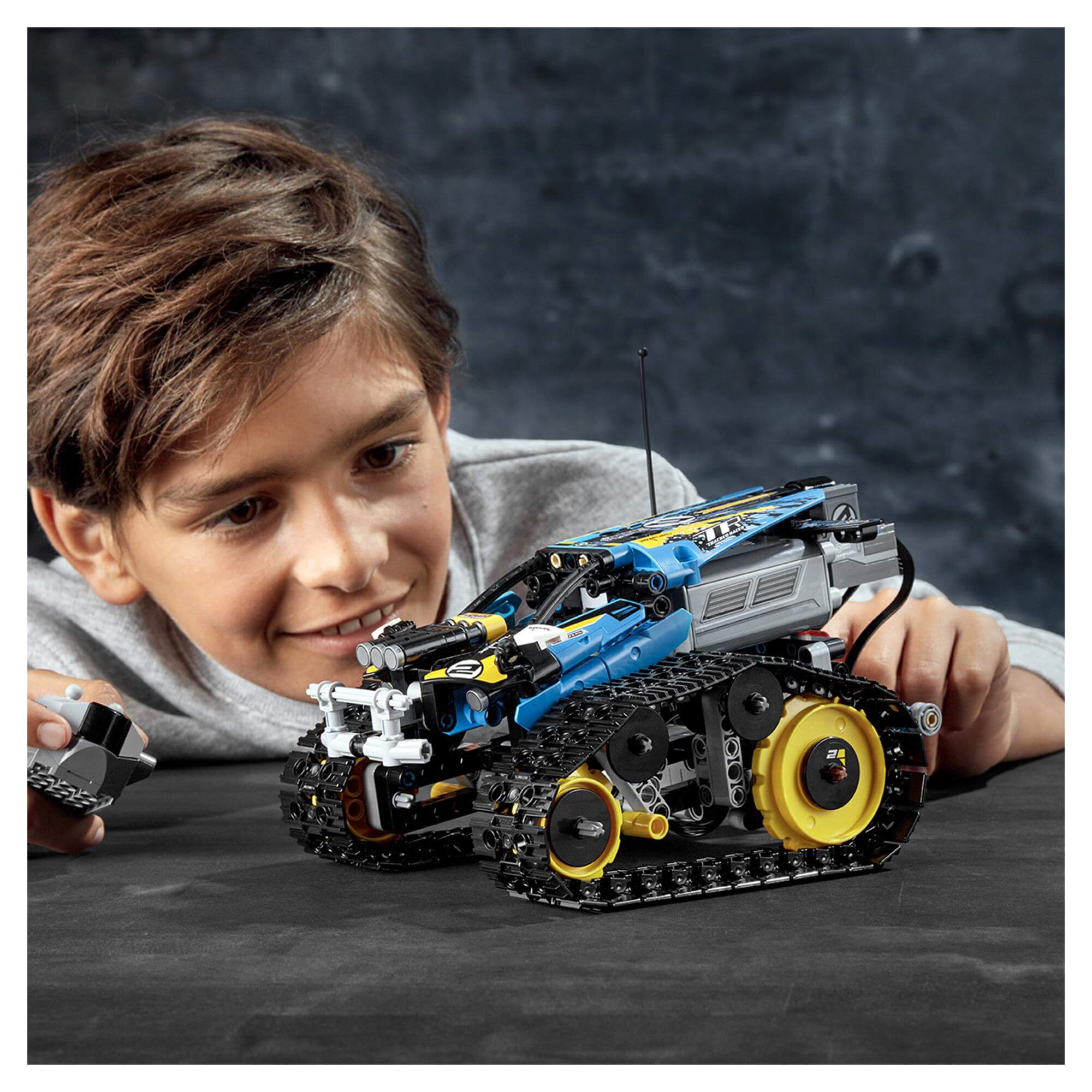 Child playing with LEGO Technic Stunt Racer RC Car Toy 42095, showcasing its remote control features and design.