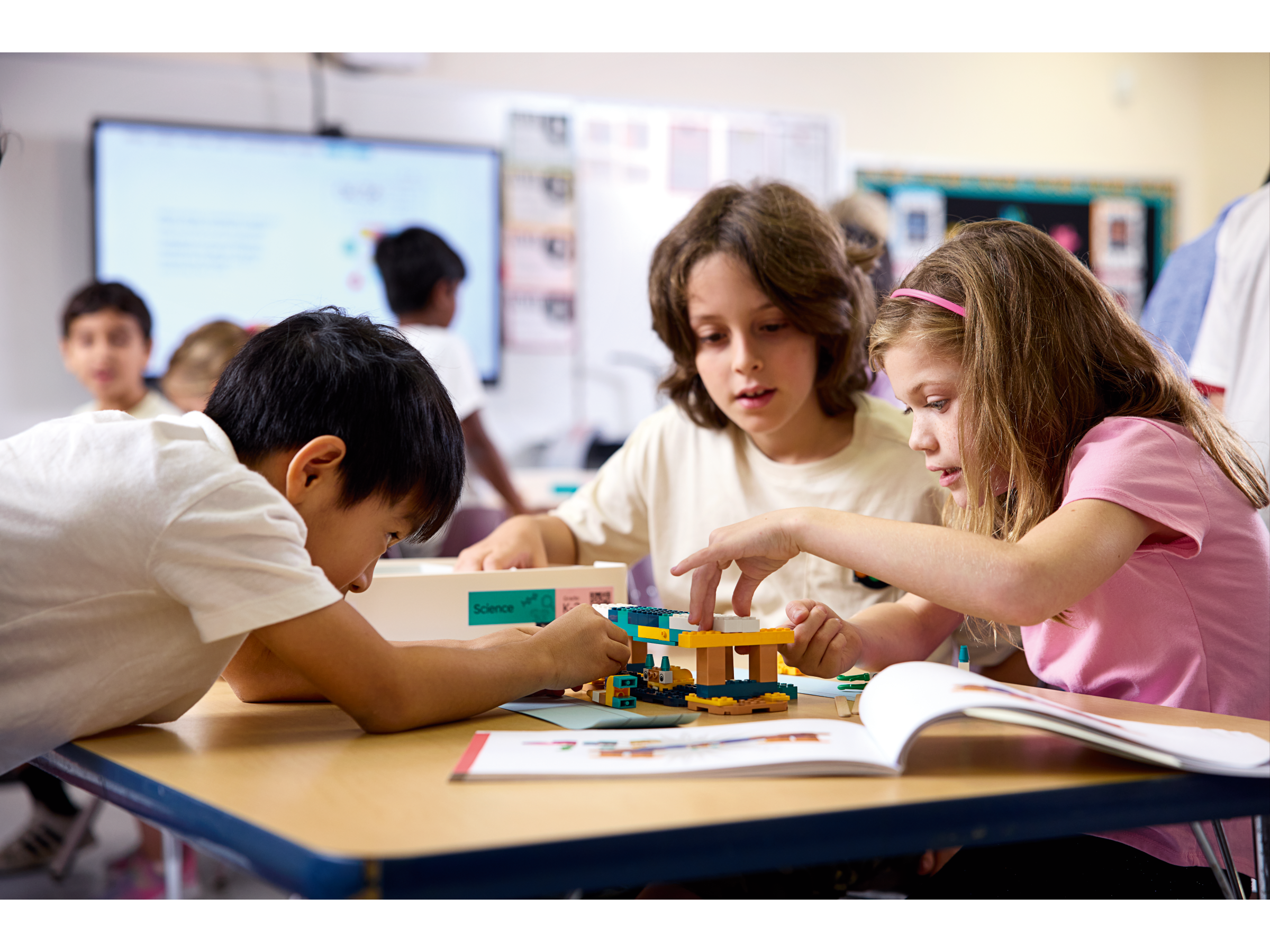 Children collaborating on a building project with LEGO blocks in a classroom setting.