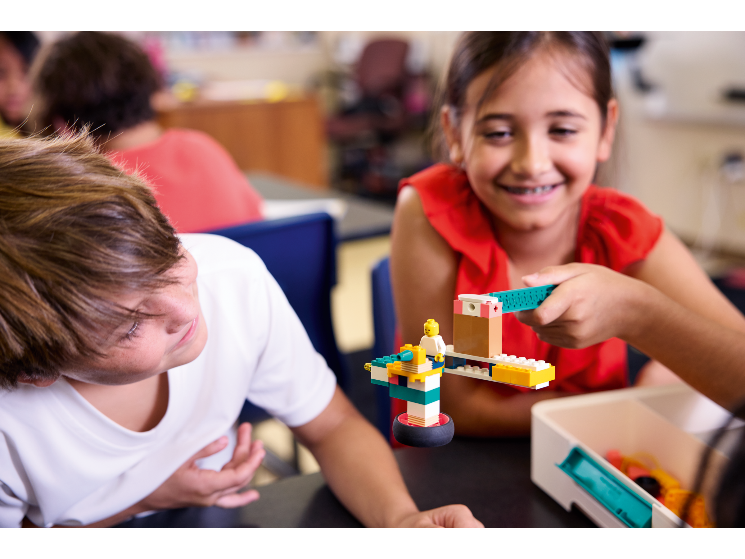 Children playing with colorful LEGO building blocks in a classroom, fostering creativity and teamwork.