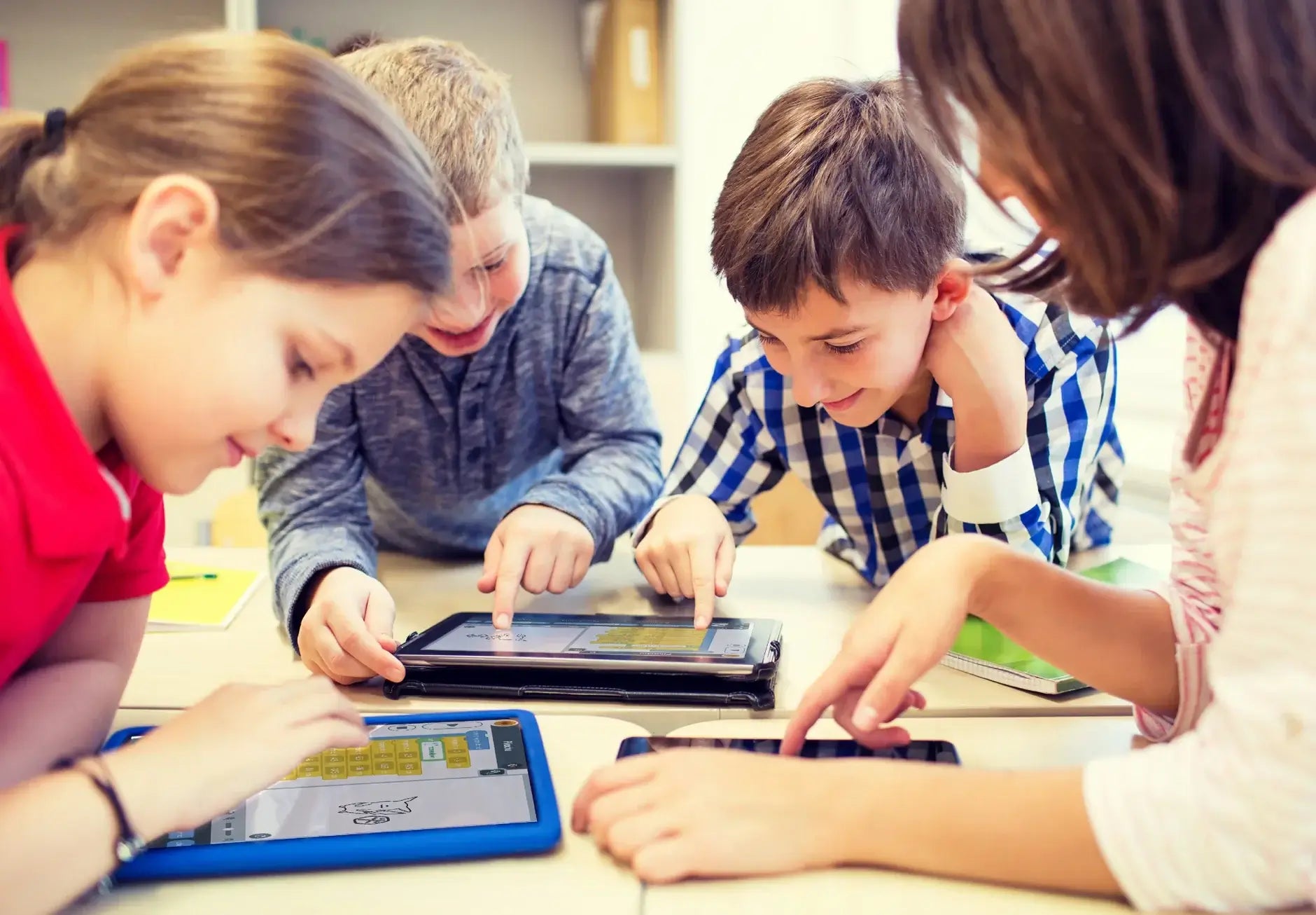 Four children engaged in interactive learning with tablets and smartphones, showcasing collaboration and technology in education.