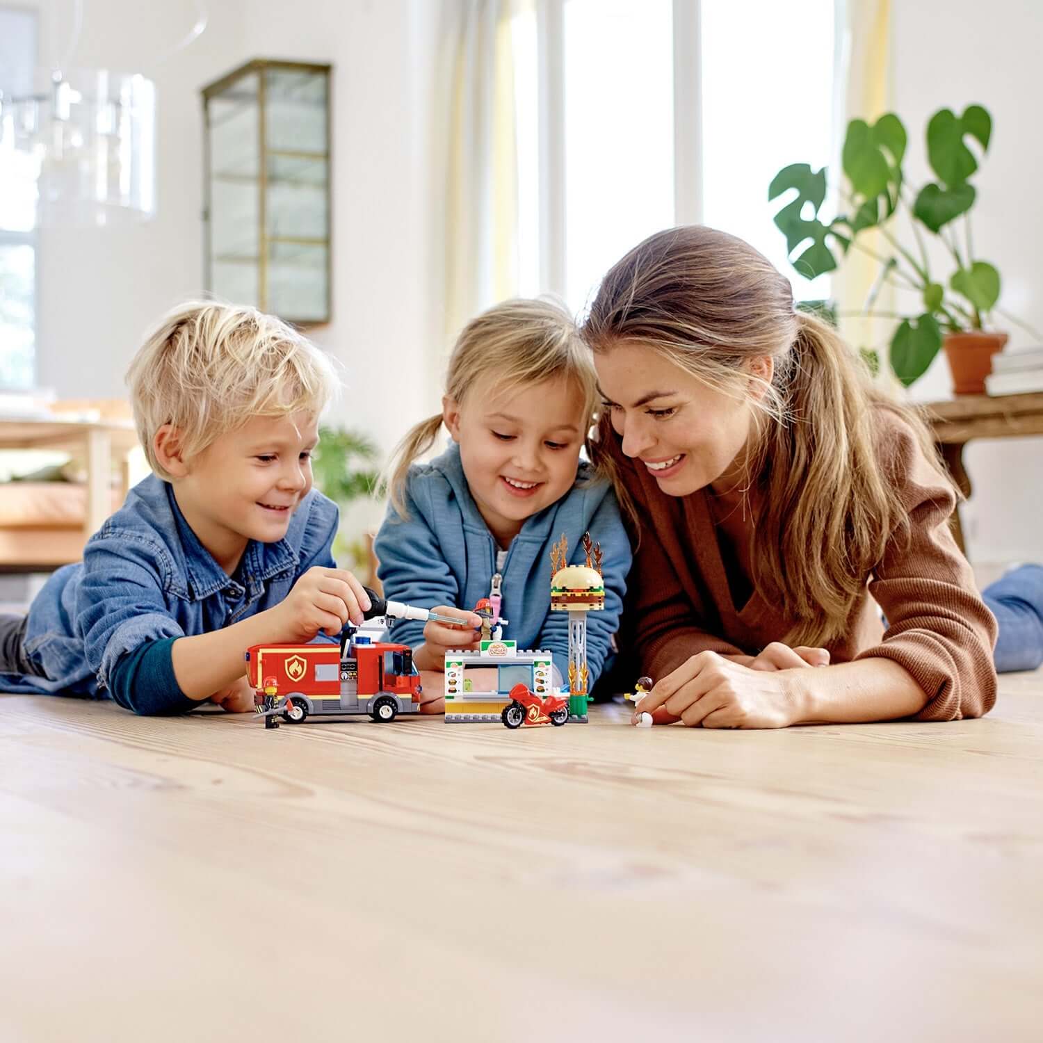 Children and a parent playing with LEGO City Burger Bar Fire Rescue Engine Toy 60214 on the floor, enjoying imaginative play.