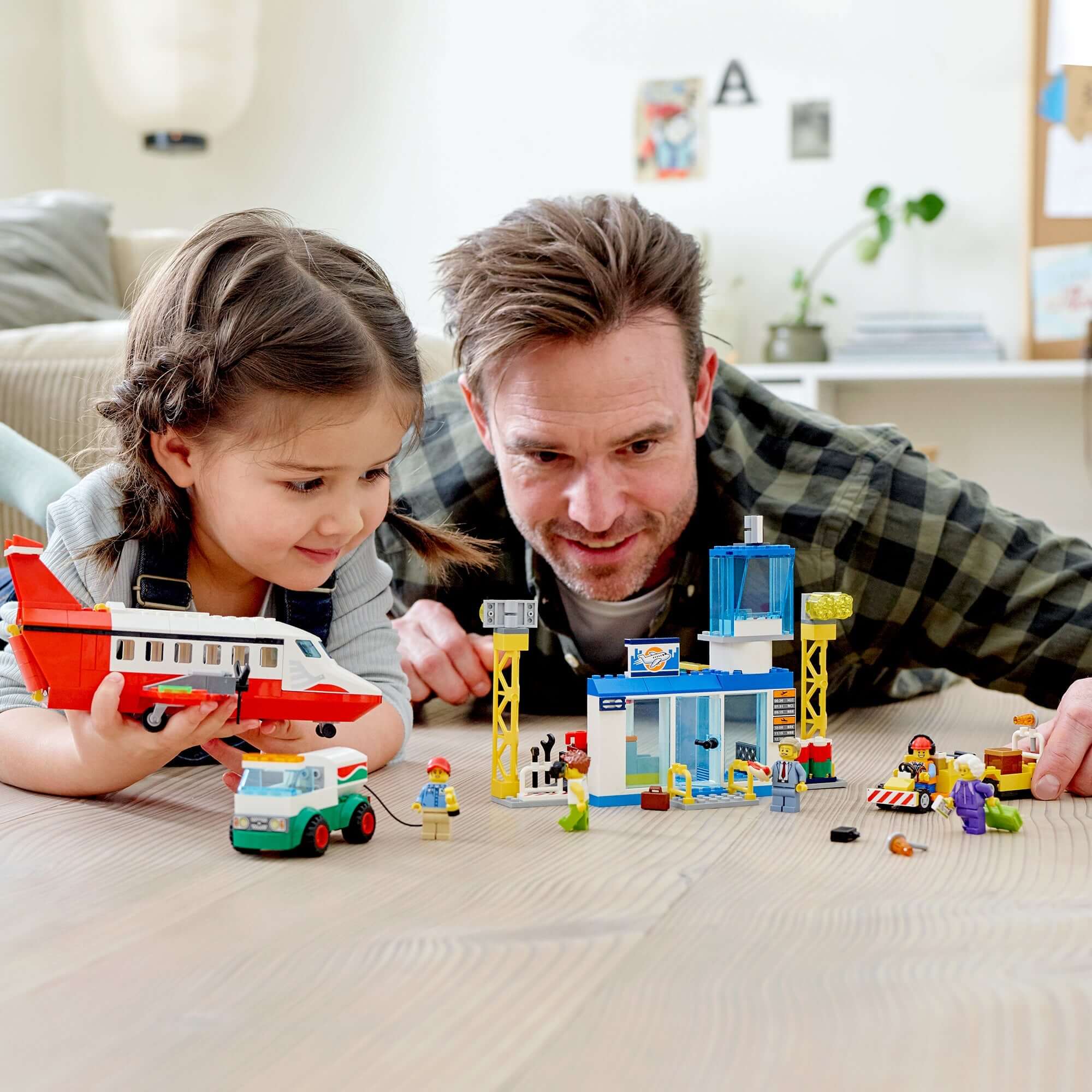 Father and daughter enjoying LEGO® City Central Airport set with charter plane and minifigures on the floor.