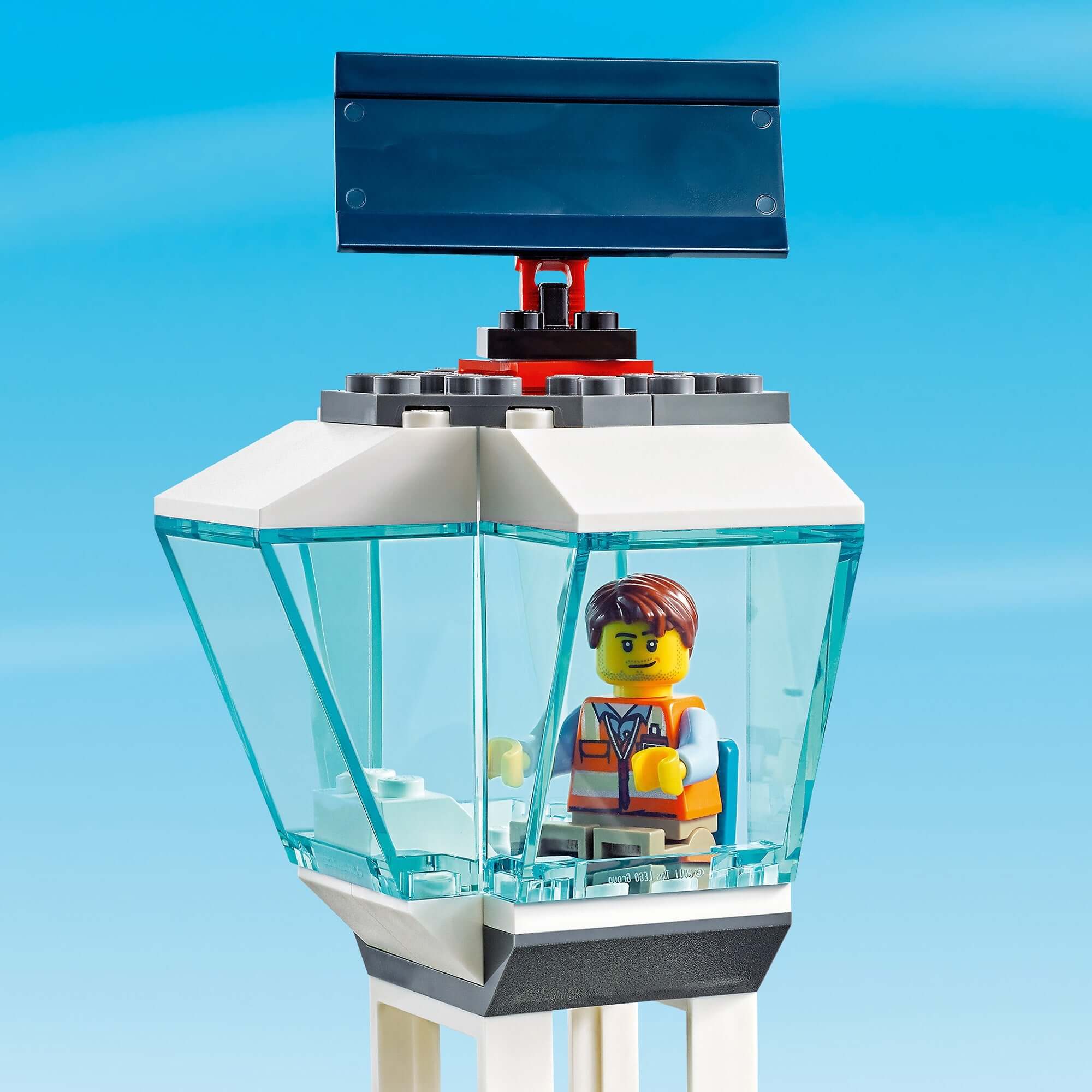 LEGO® City Airport control tower with a minifigure in a transparent cabin against a blue sky.