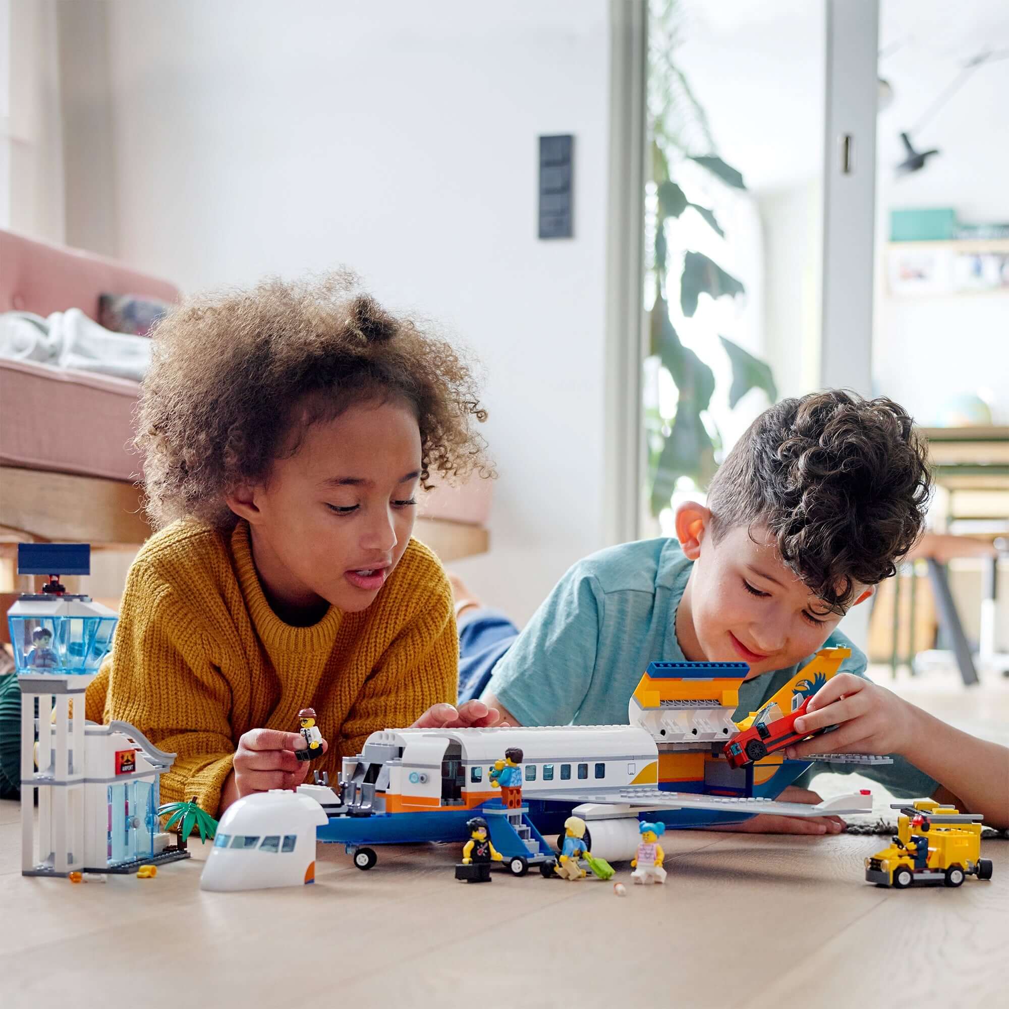 Children playing with LEGO City Airport Passenger Airplane toy, featuring figures and accessories for imaginative play.